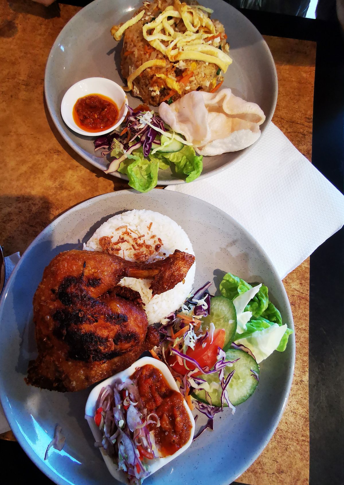 Fried rice with a prawn cracker and a grilled chicken plate with rice and salad